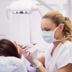 Dentist examining female patient in clinic